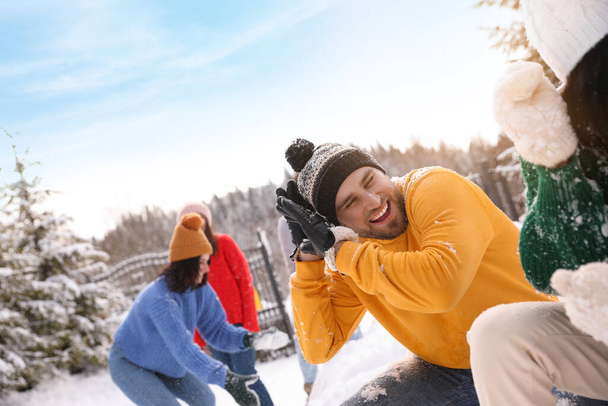 Group of friends playing snowballs outdoors. Winter vacation - Foto, imagen