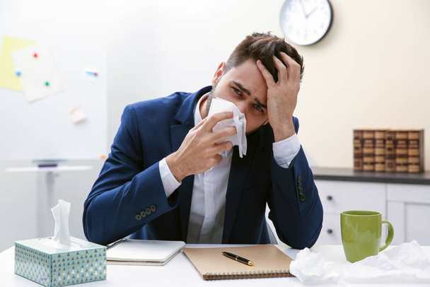 Sick young man at workplace. Influenza virus - Фото, изображение