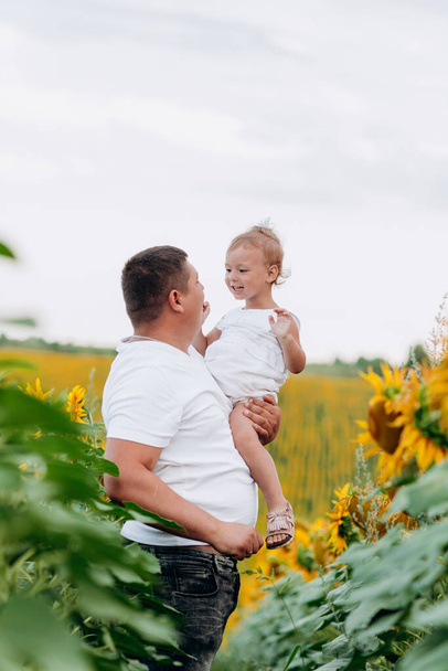 Dad with baby girl outdoors in sunflower field, love. Bonding, family, new life. Warm summer day. family concept. - Photo, Image