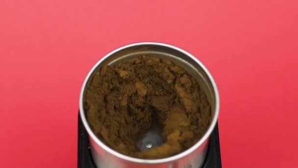 Elektrische Kaffeemühle mahlt Bohnen zu Pulver, roter Hintergrund. Morgenkonzept - Filmmaterial, Video
