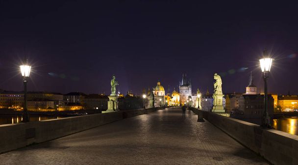 Night colorful Prague Old Town with Bridge Tower and St. Francis of Assisi Cathedral from Charles Bridge with its baroque Statues without People at the time of Coronavirus, Czech republic - Photo, Image