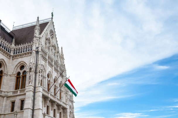 Building of the Hungarian Parliament Orszaghaz in Budapest, Hungary. The seat of the National Assembly. House built in neo-gothic style. Waving flag of Hungary on the house. Hungarian concept. - Photo, Image