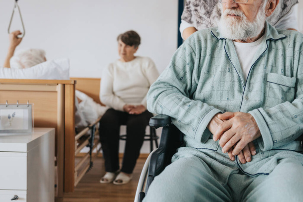 Senior man after stroke sits in a wheelchair at a nursing home - Valokuva, kuva