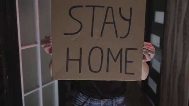 Activist young girl with a mask on her face and a poster Stay home, on cardboard - Materiał filmowy, wideo