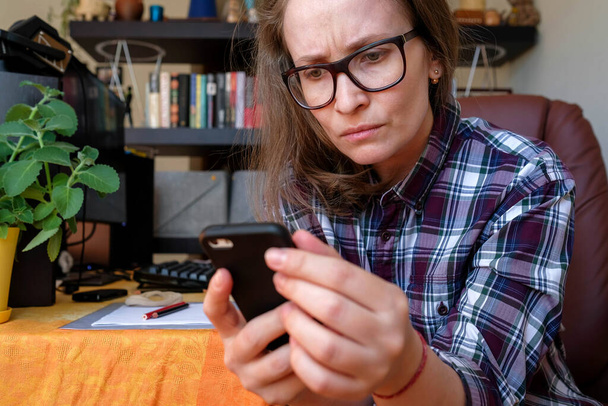 Een vrouw leest slechte informatie van een gadget. Negatieve emoties. Blijf thuis. - Foto, afbeelding