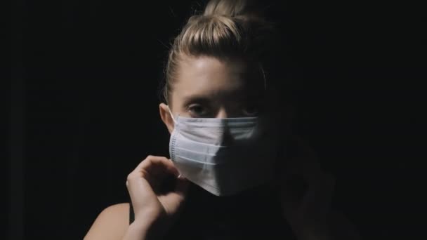 Pandemic Coronavirus. A woman who isolates at home puts on a protective mask to protect against the spread of the disease virus. Female mask, isolation on the face from coronavirus disease. - Πλάνα, βίντεο