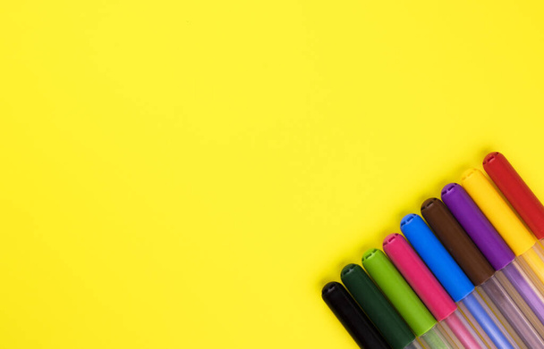 markers of different colors on a yellow background, top view. close-up markers are laid out in a row - Fotoğraf, Görsel