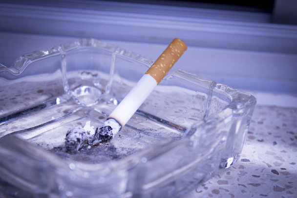 Cigarro iluminado apoiado no cinzeiro. Não há pessoas
 - Foto, Imagem