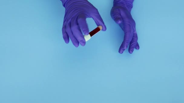 lab technician wearing latex gloves and holding medical test tube with blood sample over blue background, 4k - Video