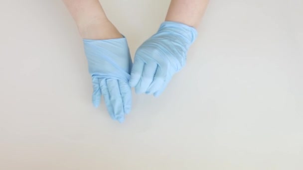 vrouw met de juiste techniek van het verwijderen van gebruikte beschermende medische handschoenen, uitzicht van boven over witte achtergrond, 4k - Video