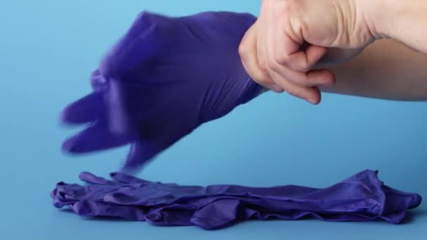 Arts het aantrekken van medische latex handschoenen ter bescherming tegen virussen en bacteriën over blauwe achtergrond, 4k - Video