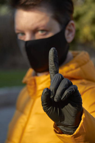 Mujer europea de mediana edad con máscara negra protectora hace un gesto de advertencia durante el coronavirus COVID-19 Mujer epidémica y enferma que usa protección durante la pandemia
. - Foto, Imagen