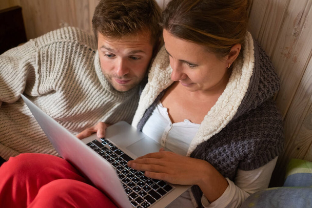 Молода пара в ліжку з ноутбуком сумно робить замовлення в інтернет-магазині. Карантин або залишитись вдома концепція
. - Фото, зображення