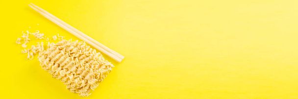 Fideos instantáneos con palos de madera. Comida rápida asiática sobre un fondo amarillo de cerca. Top vistas
. - Foto, Imagen