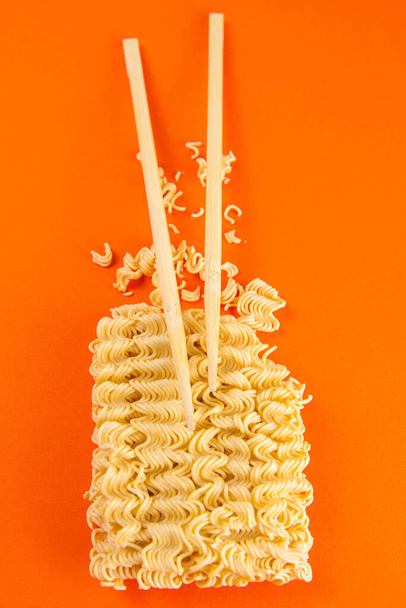 Instant Nudeln mit Holzstäbchen. Asiatisches Fast Food auf orangefarbenem Hintergrund in Großaufnahme. Top-Ansichten. - Foto, Bild