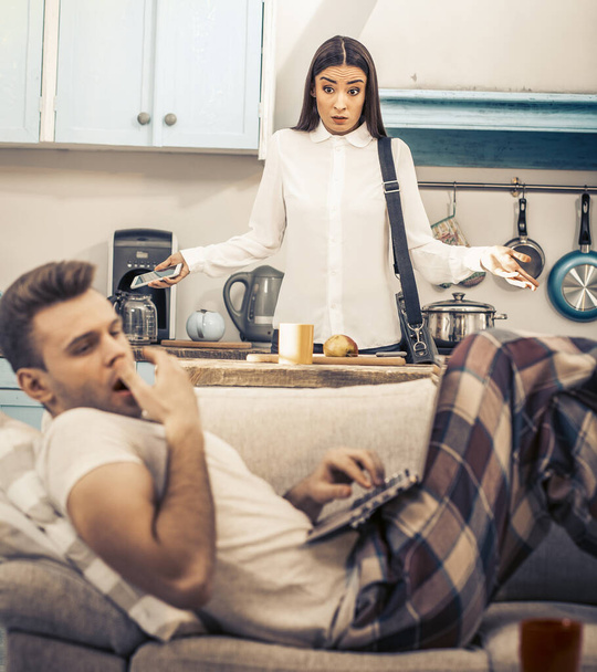 Wife angry at boring husband lying on sofa - Foto, Imagen
