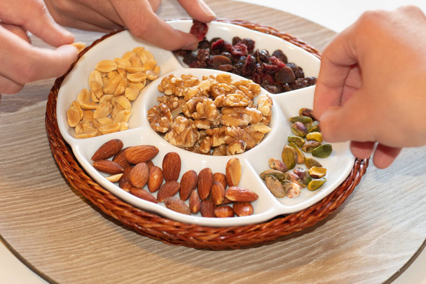 het drinken van een aantal noten als aperitief met de familie, waar u kunt zien verschillende handen houden van voedsel te eten - Foto, afbeelding
