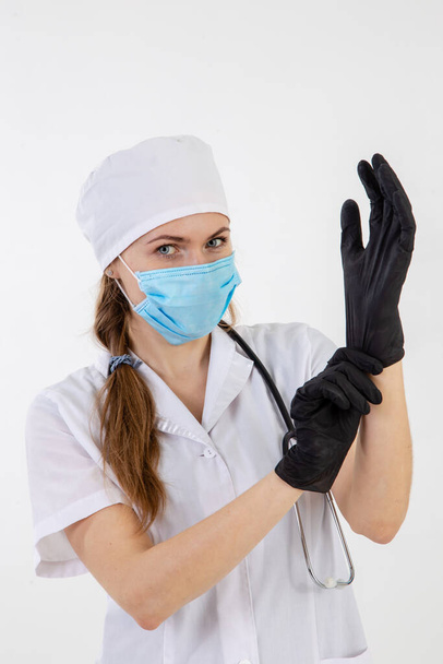 Médico con una bata blanca se pone guantes
 - Foto, Imagen