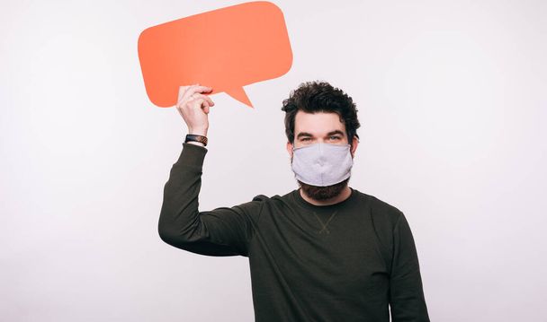 Mann mit Gesichtsmaske hält Sprechblase über weißem Hintergrund - Foto, Bild