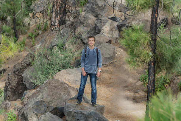 Молодий чоловік з рюкзаком подорожує західним маршрутом Тенерифе. Прогулюючись гірською стежкою, оточеною ендемічними рослинними лісами та полями лавових порід. Канарські острови. - Фото, зображення