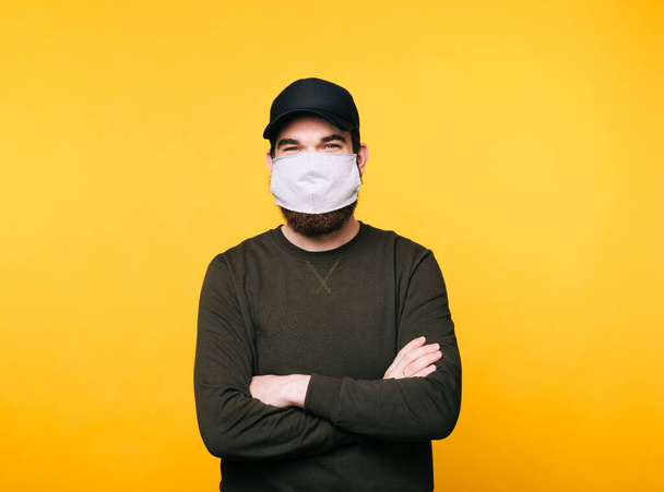 young man with facial mask looking at the camera over yellow background - Photo, Image