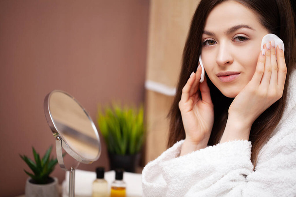Pretty girl doing cosmetic procedures at home in front of mirror - Photo, Image