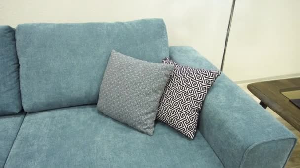 Travesseiros decorativos de designer cinza de materiais eco-friendly encontram-se no sofá azul
 - Filmagem, Vídeo