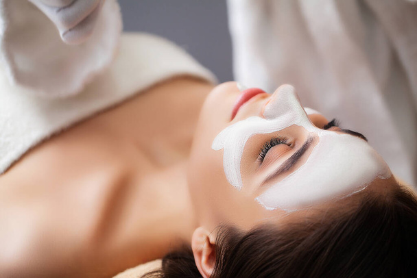 Mulher bonita aplicando máscara facial no salão de spa
 - Foto, Imagem