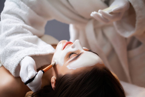 Pretty woman applying face mask at spa salon - Photo, Image