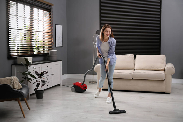 Young woman using vacuum cleaner at home - Photo, image