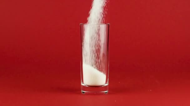 Öntsük cukor highball üveg vastag alsó piros kontrasztos háttér lassított felvétel - Felvétel, videó