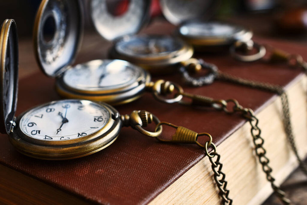 Obraz czterech zabytkowych zegarków kieszonkowych z łańcuchami na zabytkowej książce. - Zdjęcie, obraz