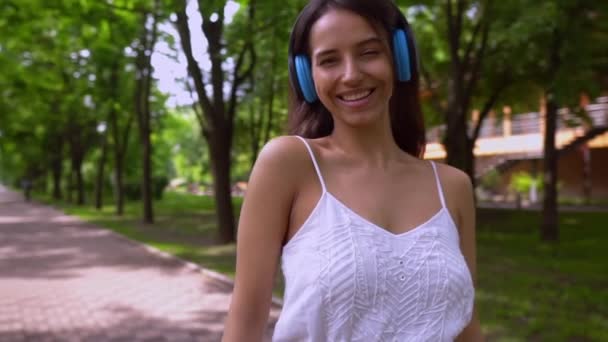 cheerful female with headphones outdoors - Záběry, video