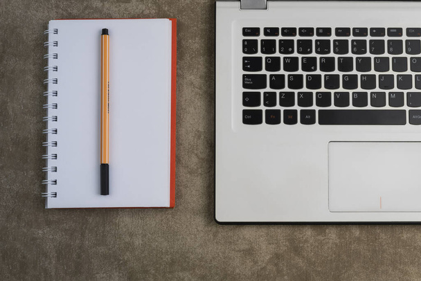 Laptop, notebook és toll barna alapon - Fotó, kép