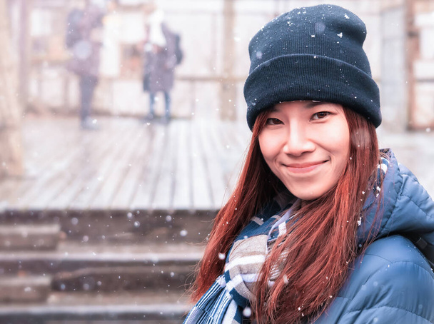 Portret Azjatki z odzieżą zimową z opadającym śniegiem w tle. - Zdjęcie, obraz