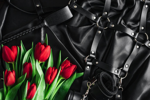 Различные секс-игрушки, установленные на черном фоне. Вид с вершины. Тюльпаны. День Святого Валентина
 - Фото, изображение