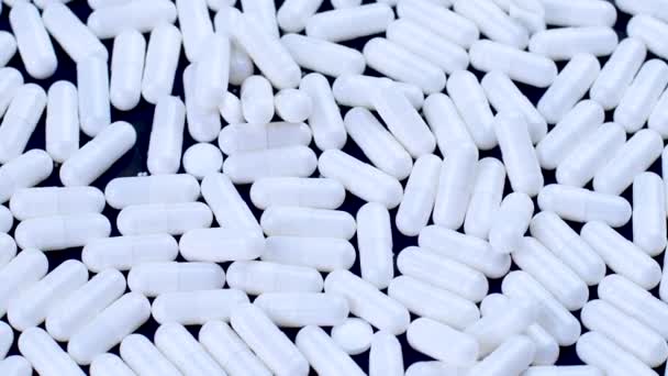 White antiviral capsules lie and rotate on a black background - Footage, Video