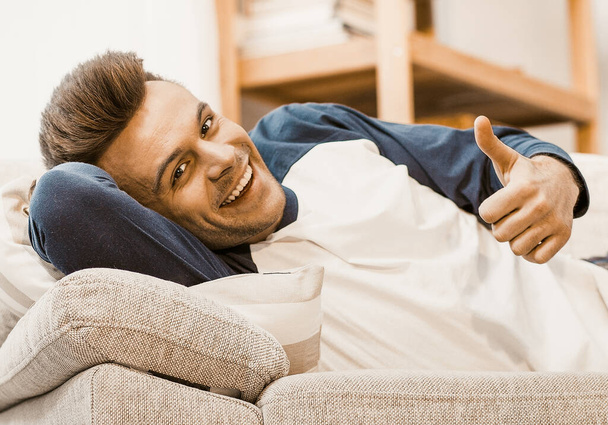 Smiling Men Shows Ok Gesture Lying Down At Sofa - Fotografie, Obrázek