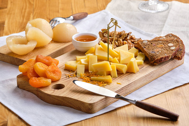 Sada různých předkrmů na víno - sýr, vlašské ořechy, sušené meruňky, med a konzervované hrušky - Fotografie, Obrázek