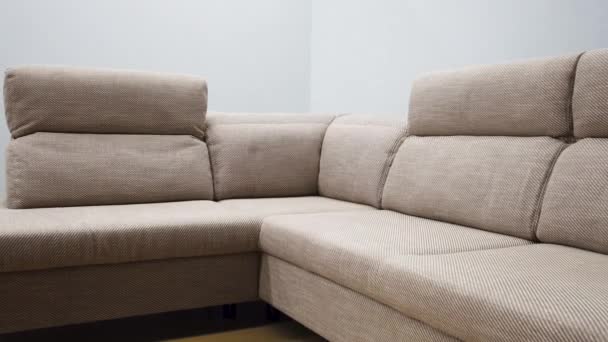 Ασκητικός γωνιακός καναπές με κομψή μπεζ υφασμάτινη ταπετσαρία - Πλάνα, βίντεο