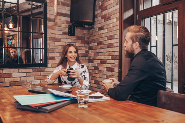 Jeune femme et homme lors d'une réunion d'affaires dans un café. Les gens d'affaires parlent d'emploi, de résoudre des problèmes en dehors du bureau
. - Photo, image