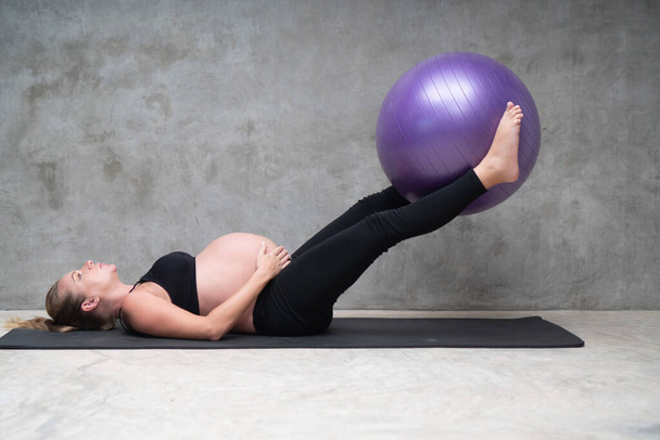 Portrait of pretty pregnant woman exercises with fitball in the gym. Working out and fitness, pregnancy concept - Foto, immagini