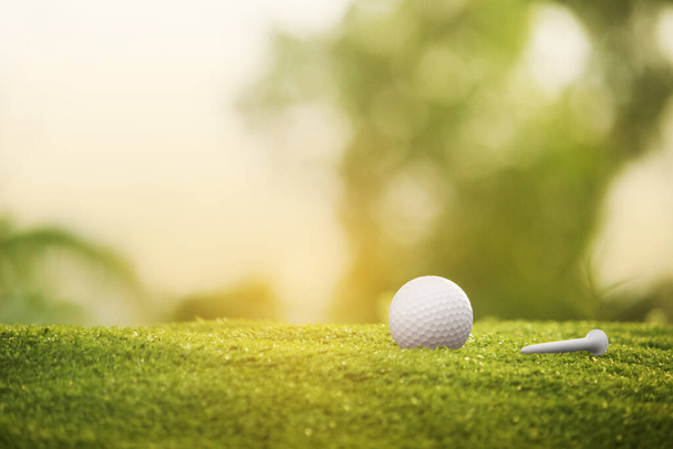м'яч для гольфу на зеленому газоні в красивому полі для гольфу з ранковим сонячним світлом. Готовий до гольфу в першій короткометражці. Спорт, який люди по всьому світу грають під час канікул для здоров'я
. - Фото, зображення