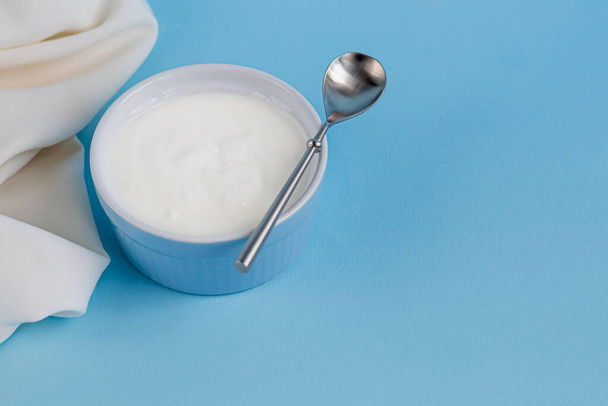 Domowej roboty jogurt w dwóch szklankach na niebieskim tle. Ozdobiona miętą i żurawiną. Zdrowa dieta. Wegetariańskie jedzenie. Przestrzeń kopiowania - Zdjęcie, obraz