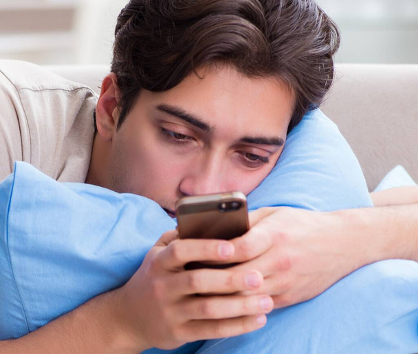 Man addicted to his mobile phone in bed - Foto, imagen