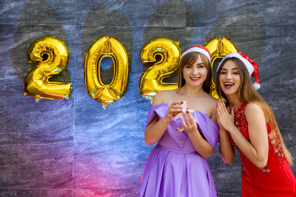 Портрет двух красивых девушек в новогоднюю ночь в элегантных вечерних платьях
 - Фото, изображение