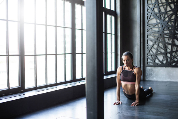 Sports woman working out on the floor in a room with floor-to-ceiling window. Workout. - Foto, immagini