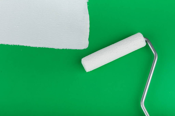 painting roller and strip of white paint on green background - Foto, Imagem