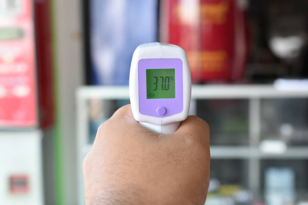 hand thermometer scanner in de winkel voor binnenkomst  - Foto, afbeelding