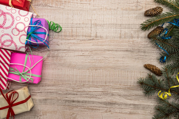 Концепция рождественских подарков Отделения ели с конусами и разноцветными подарочными коробками на столе
 - Фото, изображение